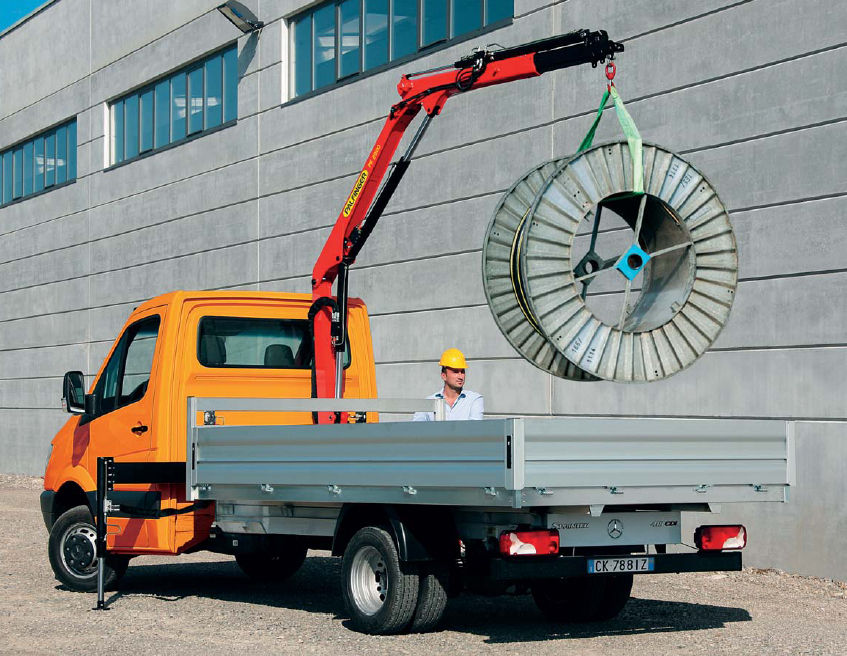A wire spool being lifted into a truck.